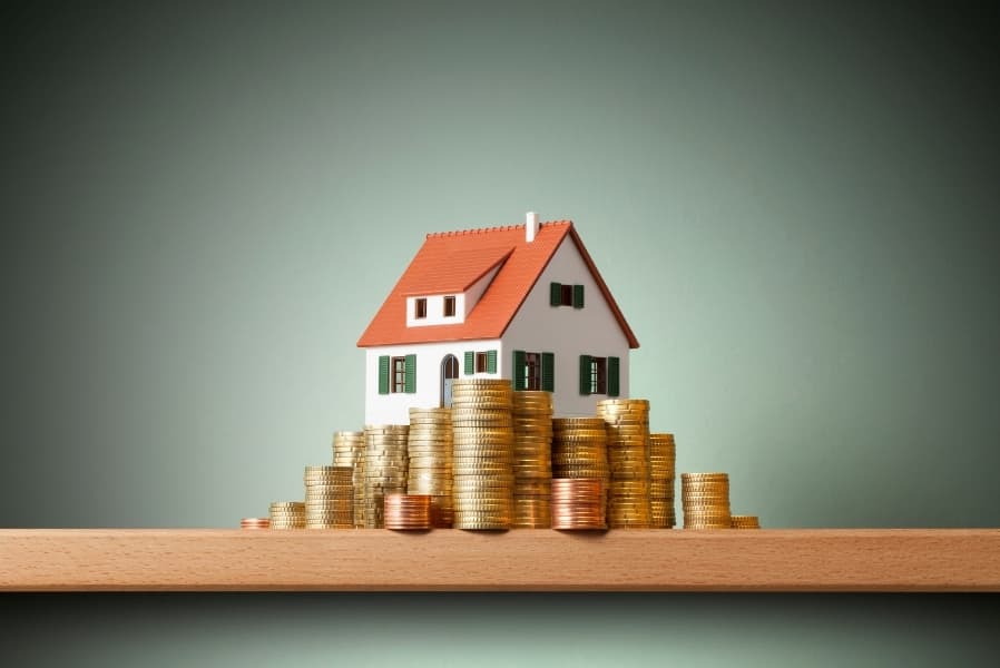 Model home beside stacks of coins representing First Home Savings Account growth